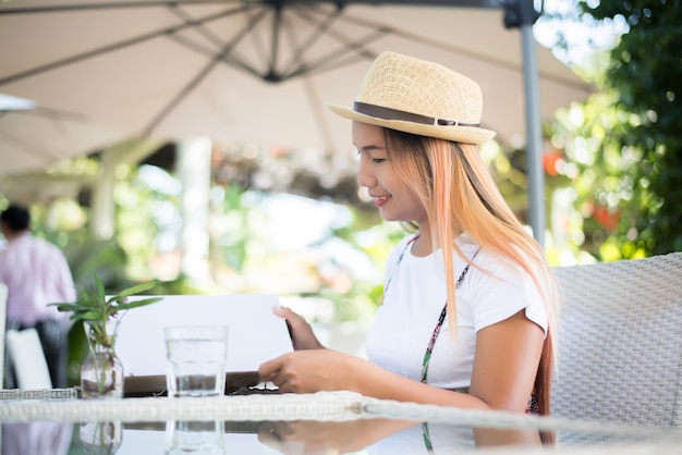 Smiling Young woman in a restaurant with the menu in hands, Young Woman Choosing from a Restaurant Menu