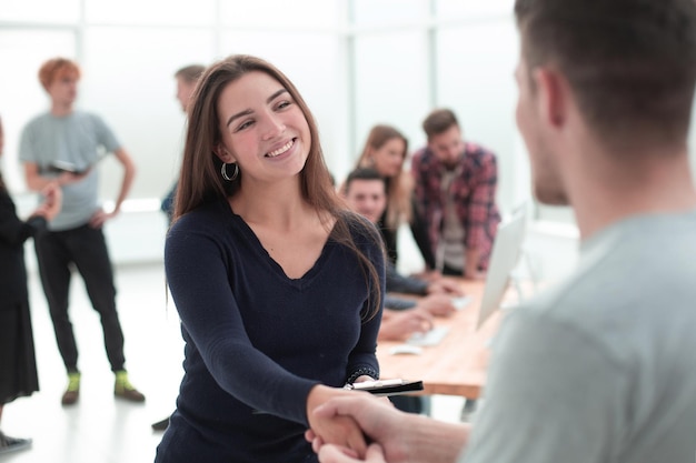 Smiling young woman shaking hands with the customer