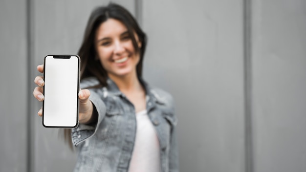 Smiling young woman showing smartphone 