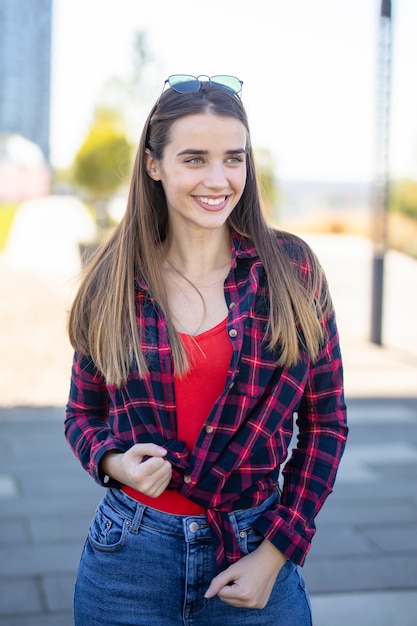 Smiling young woman standing outside on the street on sunny summer or spring day