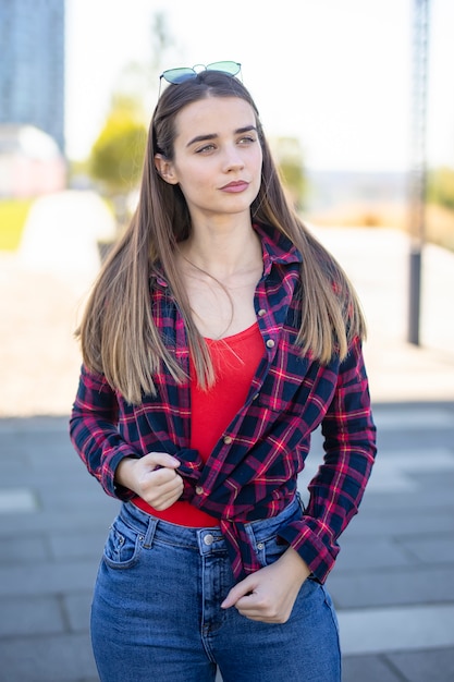 Smiling young woman standing outside on the street on sunny summer or spring day