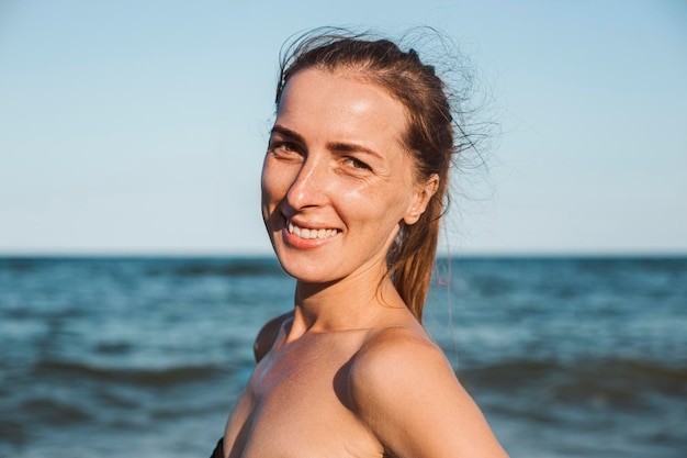 Smiling young woman in a swimsuit without makeup at the sea