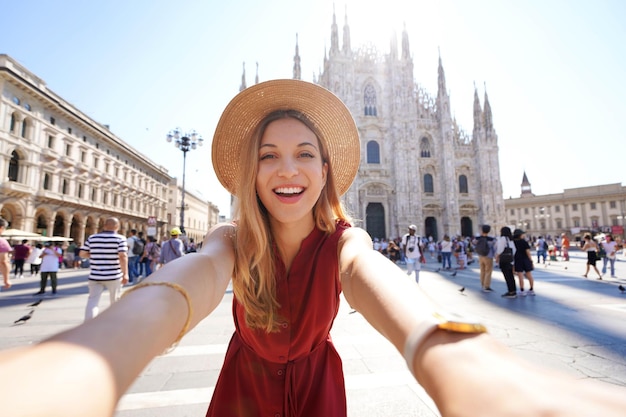 Smiling young woman takes selfie picture in the city of Milan Italy Laughing girl having fun on her vacation in Europe