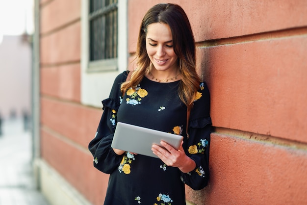 Smiling young woman using digital tablet outdoors.