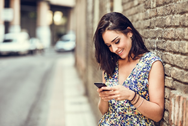 Smiling young woman using her smart phone outdoors.