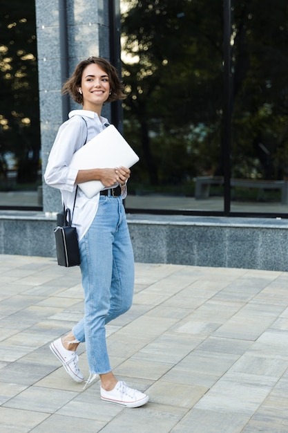 Smiling young woman walking outdoors at the street