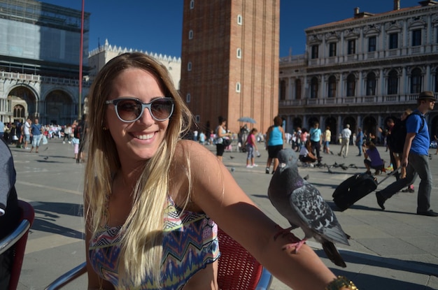 Smiling young woman wearing sunglasses while standing in city