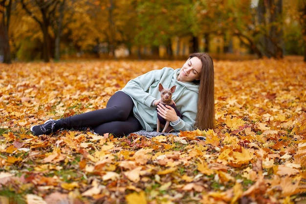 Smilling attractive wowan lying with dog toyterrier in the autumn park