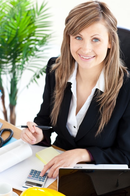 Smilling businesswoman working in her office with a calculator