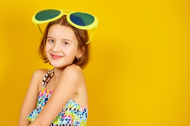 Smilling Child teenager girl in swimsuit and big sunglasses posing