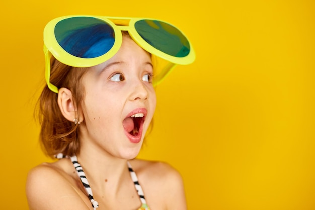 Smilling Child teenager girl in swimsuit and big sunglasses posing