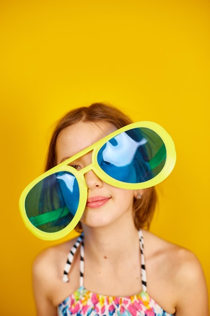 Smilling Child teenager girl in swimsuit and big sunglasses posing