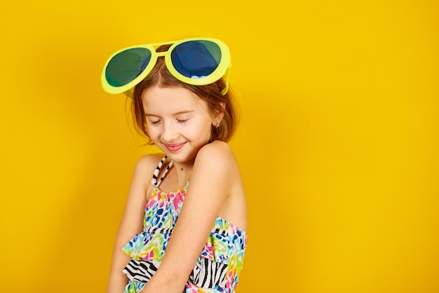 Smilling Child teenager girl in swimsuit and big sunglasses posing