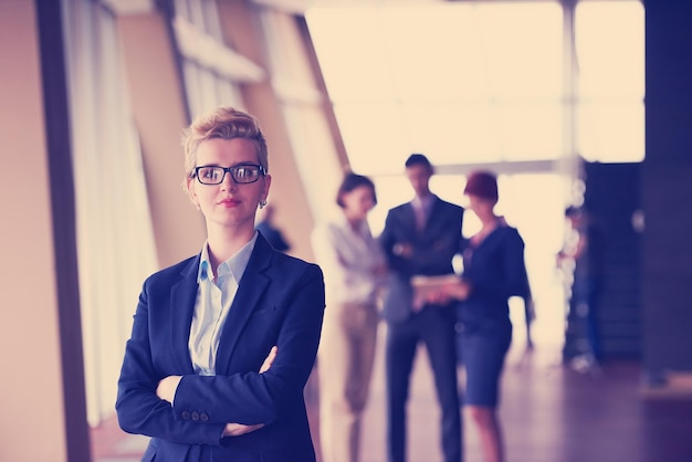 Photo smilling young business woman in front her team blured in background. group of young business people. modern bright  startup office interior.