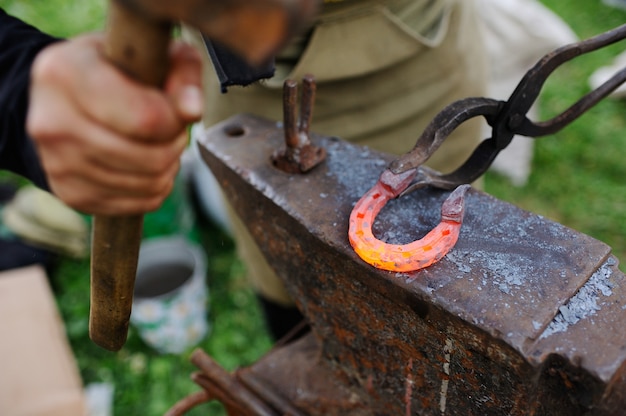 Photo the smith makes a horseshoe on the anvil