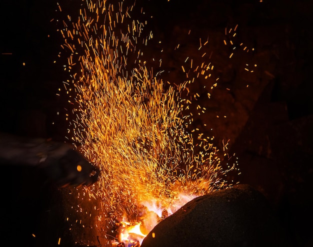 Smithy fire flame tips with sparks closeup on dark background