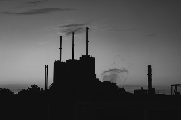 Smoke emitting from factory against sky