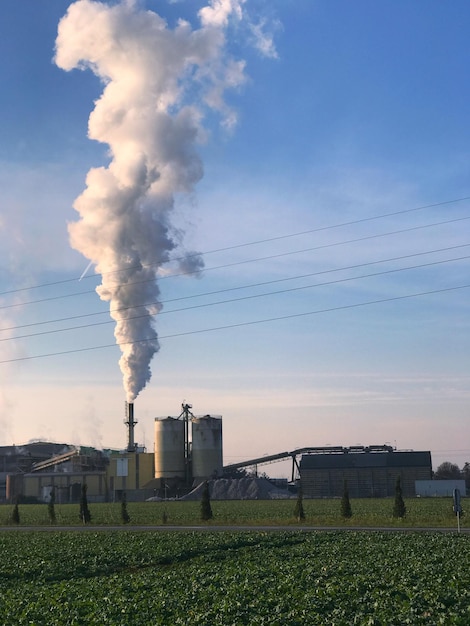 Smoke emitting from factory against sky