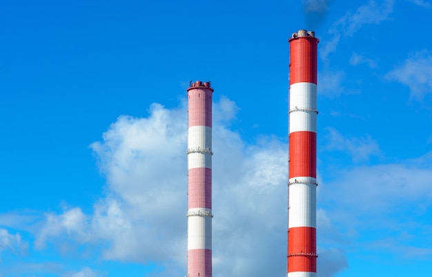 The smoke from the chimneys against the blue sky with clouds