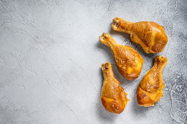 Smoked chicken leg drumsticks on a kitchen table. White background. Top view. Copy space.