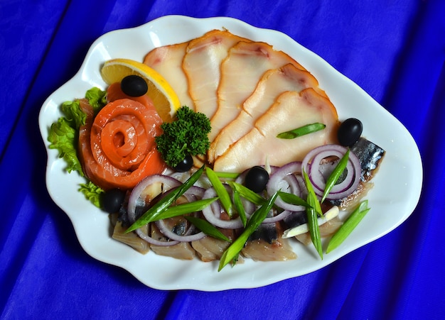 Smoked fish in a plate on a silk tablecloth