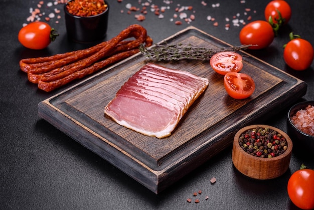 Smoked ham on a dark concrete table with addition of fresh aromatic herbs and spices natural product from organic farm