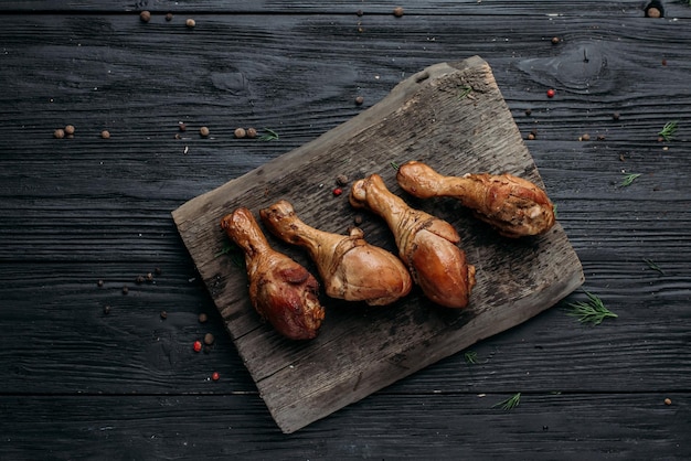 Smoked homemade chicken drumstick on a wooden background and an old wooden hot smoked stick