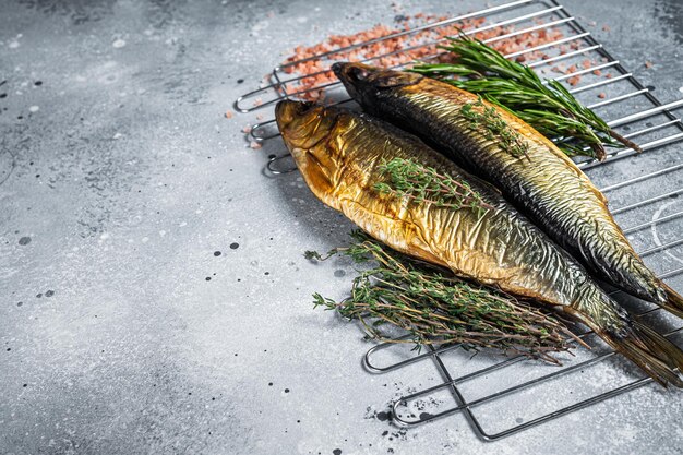 Smoked kippered whole herrings on smoker grill. Gray background. Top view. Copy space.