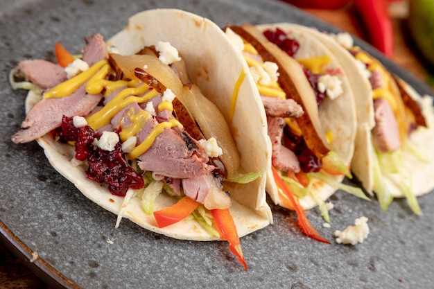 Smoked meat tacos served on a black plate.