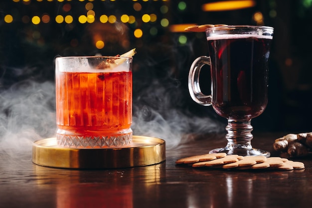 Smoked old fashioned cocktail and mulled wine on the table on dark background