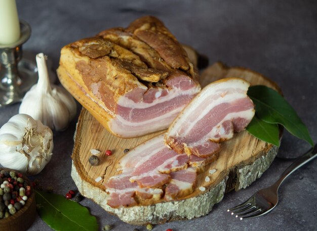 Smoked pork belly on a cutting board against a dark background