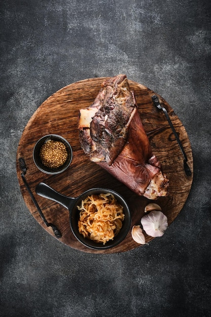 Smoked pork knuckle with stewed cabbage on a wooden tray