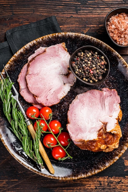 Smoked pork meat - gammon with herbs on rustic plate. Wooden background. Top view.