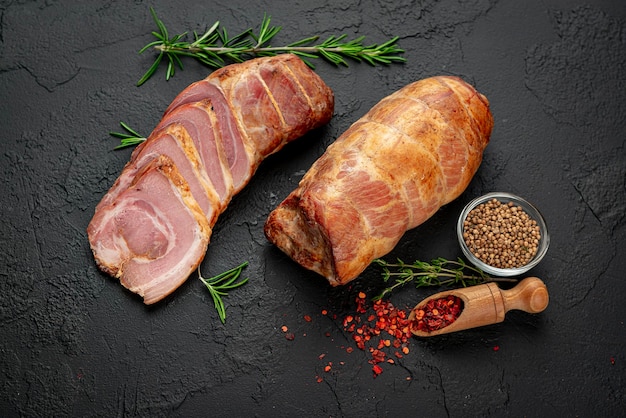 Smoked pork roll with spices on a dark background