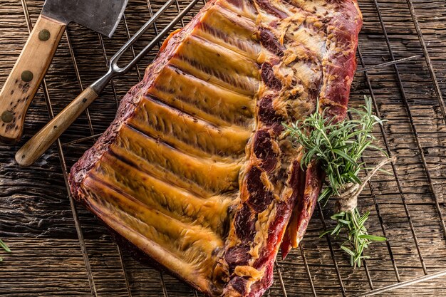 Smoked raw pork ribs and rosemary herbs on wooden board.