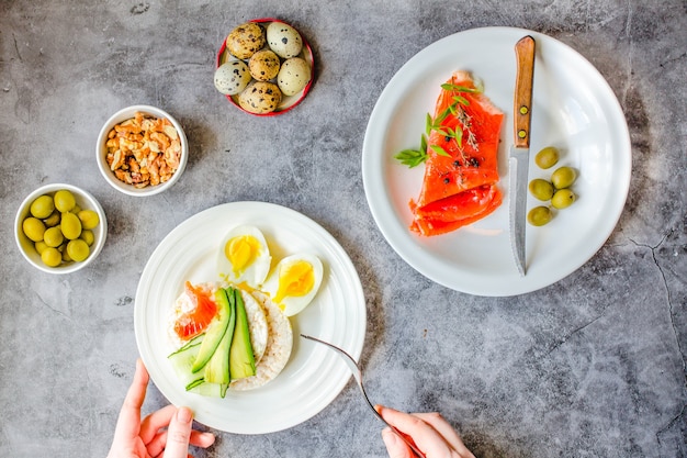 Smoked red fish salmon with olive, quail eggs, nuts and rice crispy cakes with avocado on a gray background. Top view. Rustic. Products with omega-3 good for healthy hair and skin. Space for text.