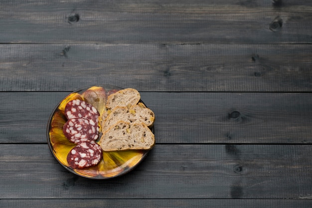 Smoked sausage with walnut bread on a clay plate.