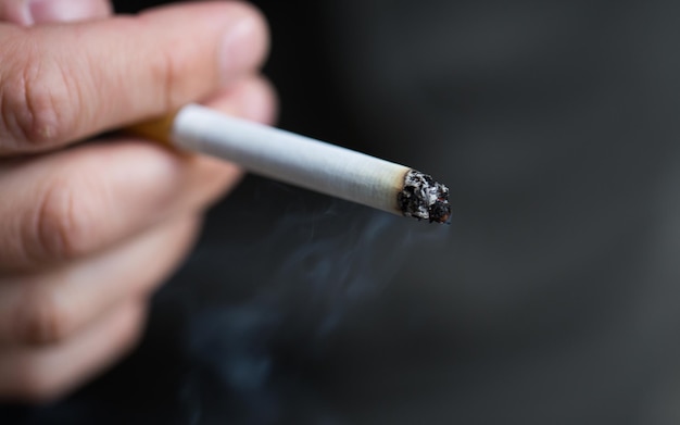 smoking, substance abuse, addiction, people and bad habits concept - close up of male hand with cigarette