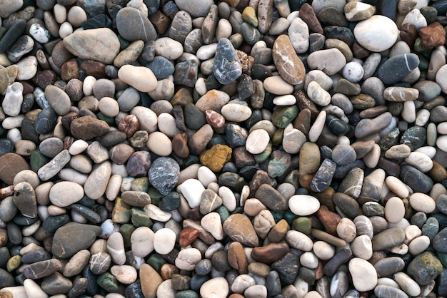 Smooth round wet pebbles texture background Pebble sea beach closeup