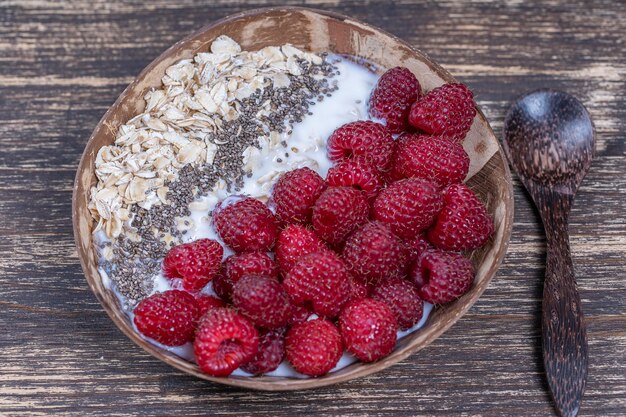 Smoothie in coconut bowl with raspberries oatmeal and chia seeds for breakfast close up The concept of healthy eating superfood