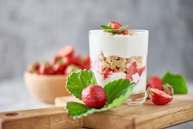 Smoothie with summer strawberry in glass jar and fresh berries  in wooden bowl on a gray