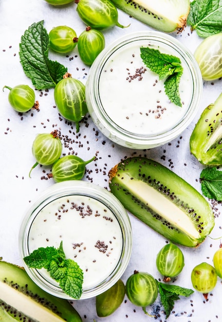 Smoothies and milkshakes from gooseberry milk cocktail with kiwi and yogurt chia seeds gray kitchen table background flat lay top view