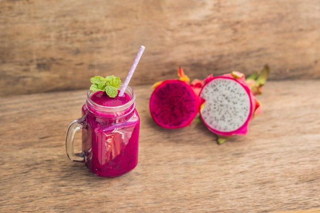 Smoothies of a red organic dragon fruit on an old wooden table