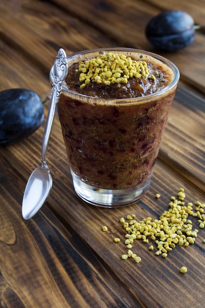 Smoothies with blue plums and bee pollen on the wooden background Closeup Location vertical