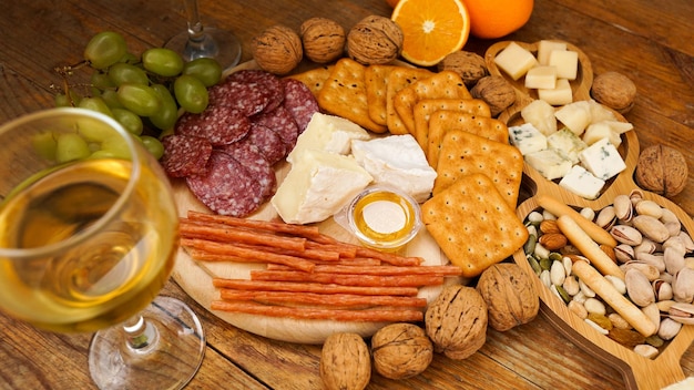 Snack for wine Cheese and meat plate Sausage cheese nuts grapes crackers on wooden table Italian food for romantic date or meeting with friends