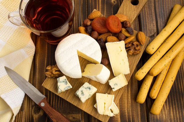 Snack  with cheeses and bread sticks on the brown  wooden background.View from above.