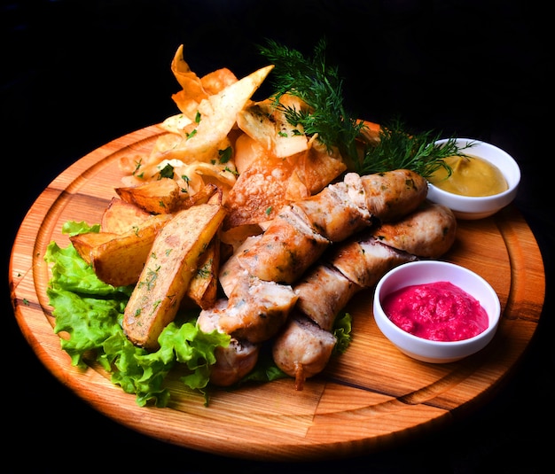 Snacks to beer on a wooden board. Bavarian fried sausages, fried potatoes, chips isolated