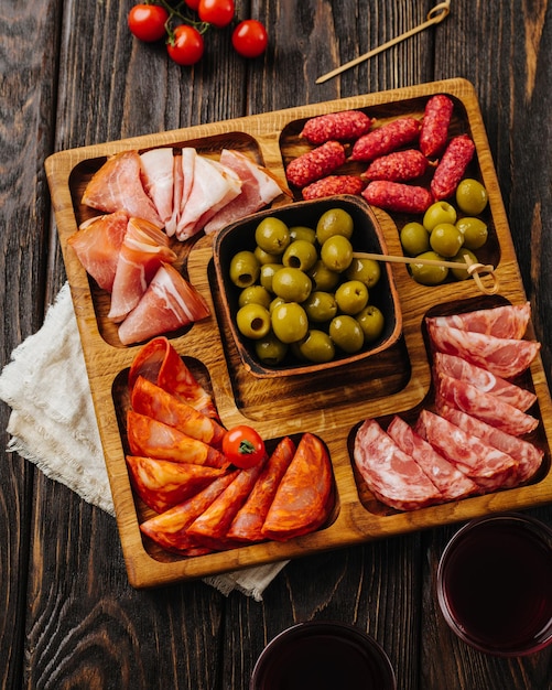 Snacks for wine on a wooden board menazhnitsa with sausage olives and cherry tomatoes