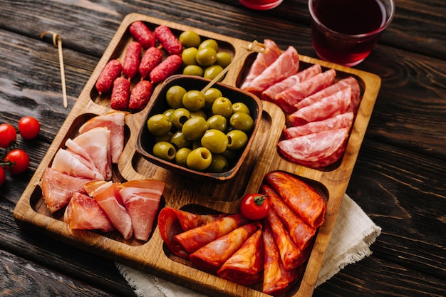 Snacks for wine on a wooden board menazhnitsa with sausage olives and cherry tomatoes