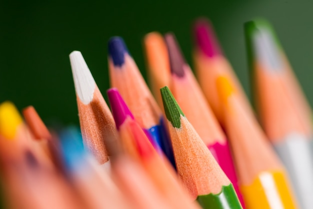 snapshot of pencils of different colors on a green background, with a small depth of field, macro.